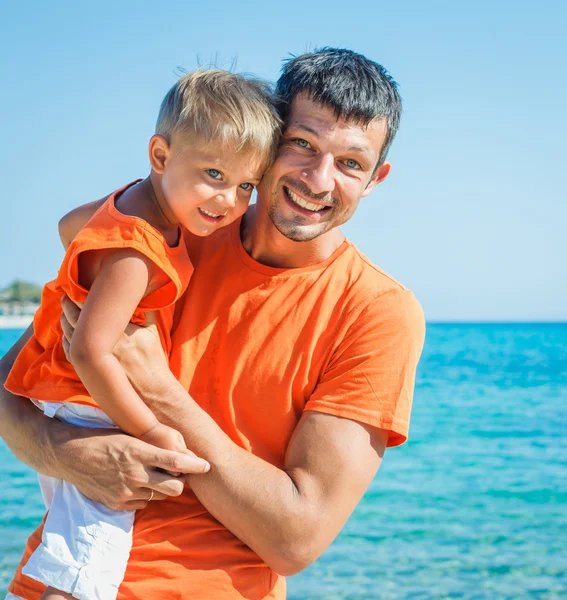 Clouseup retrato de pai feliz com o filho rindo e olhando para a câmera na praia — Fotografia de Stock