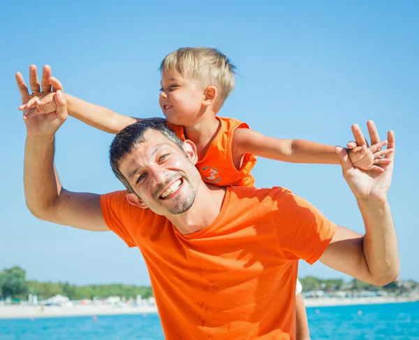 Портрет счастливого отца с сыном, смеющимся и смотрящим в камеру на пляже — стоковое фото