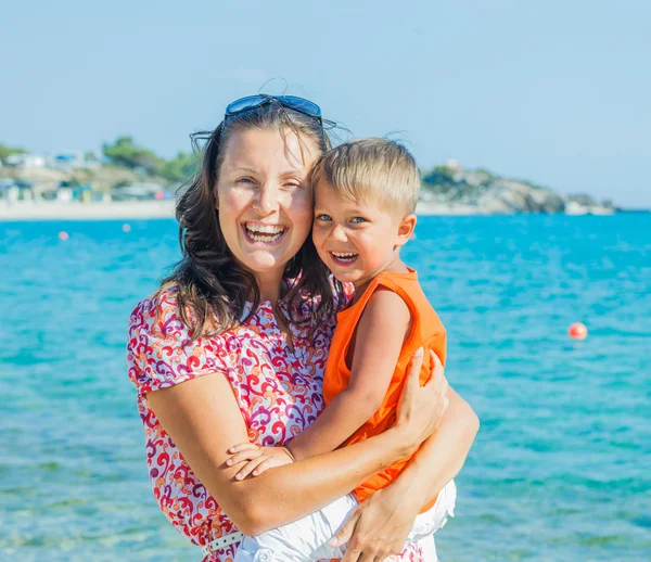笑いと、ビーチ上カメラ目線の息子と一緒に幸せな母の clouseup の肖像 — ストック写真