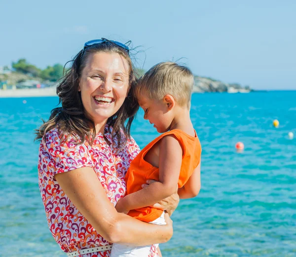 Clouseup portret szczęśliwy matki z synem, śmiejąc się i patrząc na kamery na plaży — Zdjęcie stockowe