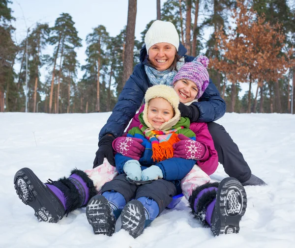 Mamma med hennes två barn pulka i vinterlandskap — Stockfoto