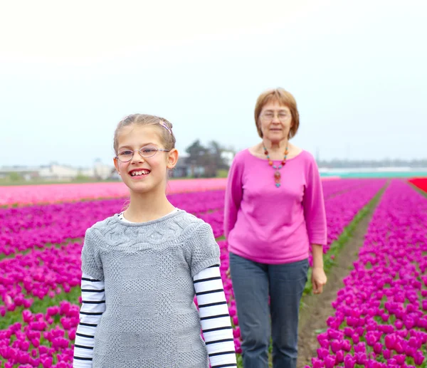 Dívka s babičkou v poli fialové tulipány — Stock fotografie