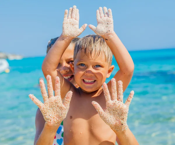 Närbild bild av händerna av flickan och pojken på sandstranden — Stockfoto