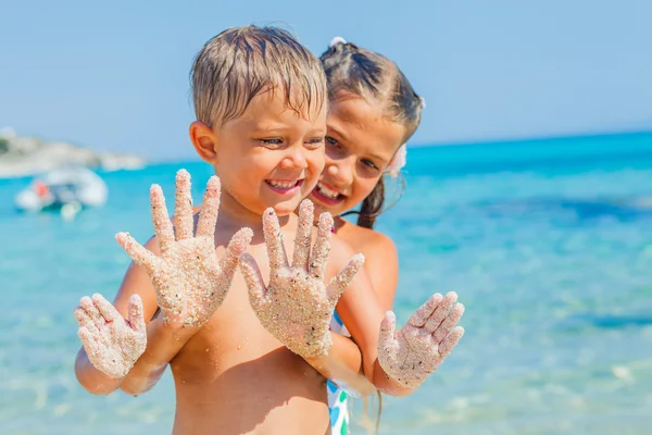 Närbild bild av händerna av flickan och pojken på sandstranden — Stockfoto