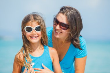 Anne ve kızı plajda güneş gözlüğü