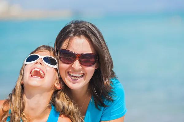 Mother and her daughter in sunglasses on beach — Stock Photo, Image