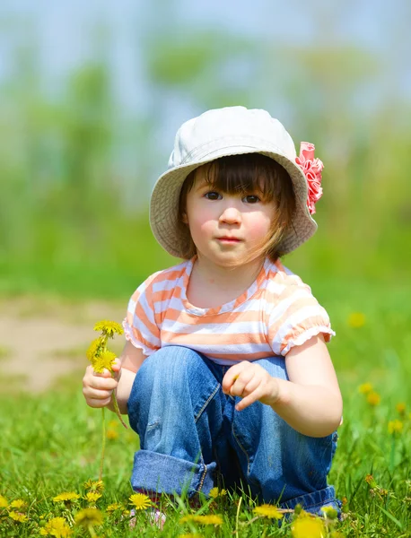 Meisje zit onder paardebloemen — Stockfoto