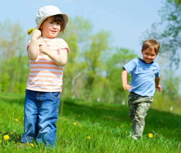 Girl sitting among dandelions — Stock Photo, Image