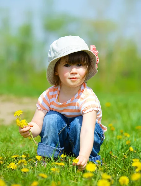 Dandelions arasında oturan kız — Stok fotoğraf