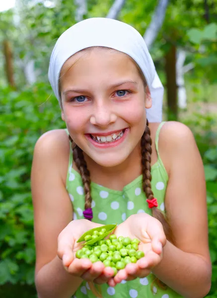 Portret van mooi meisje houdt van groene erwten in tuin — Stockfoto