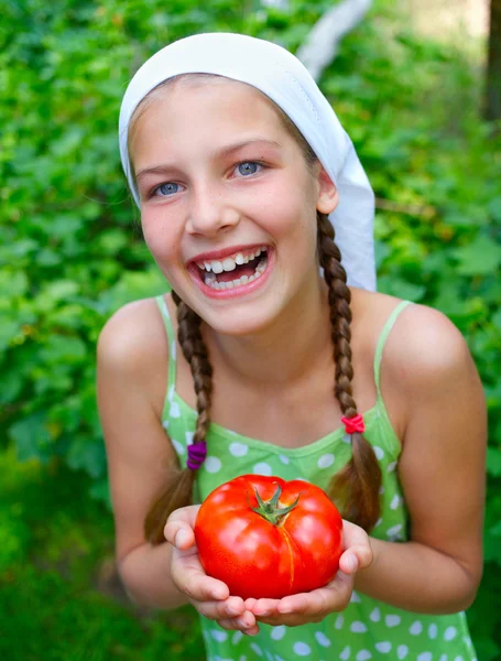 Portrait of beautiful girl holding tomato in green garden — Stock Photo, Image