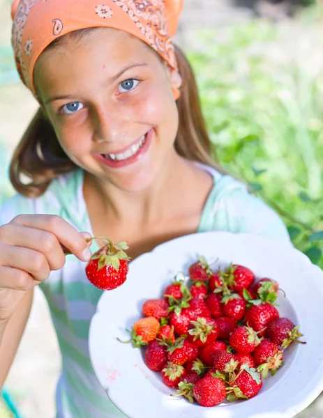 Krásná holčička usmívající se jíst jahody v zahradě — Stock fotografie