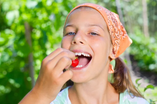 Beautiful little smiling girl eating strawberries in garden — Stock Photo, Image