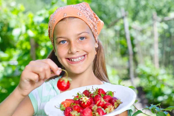 Mooie lachende meisje aardbeien eten in tuin — Stockfoto