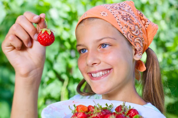 Mooie lachende meisje aardbeien eten in tuin — Stockfoto