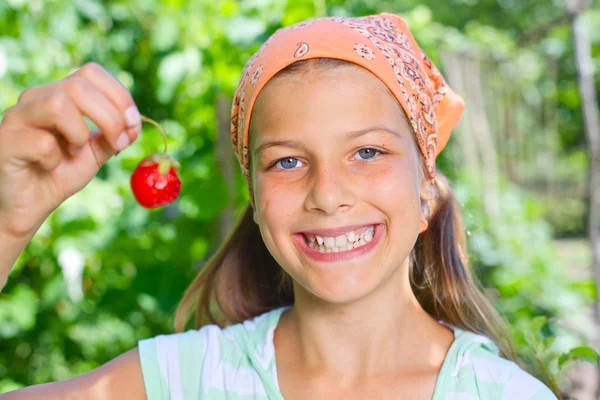 Linda menina sorridente comendo morangos no jardim — Fotografia de Stock