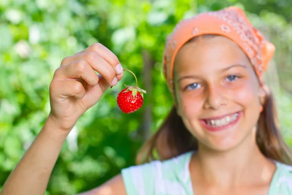 Linda menina sorridente comendo morangos no jardim — Fotografia de Stock