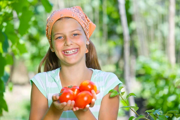 Portrait of beautiful girl holding tomatoes in green garden — Stock Photo, Image