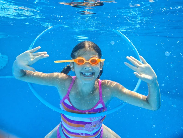 Den søte jenta svømmer under vann og smiler. – stockfoto