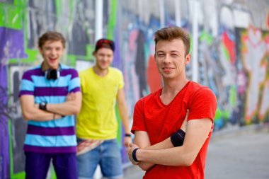 Portret van gelukkig tieners jongen met zijn vrienden door geschilderde muur camera kijken. verticale weergave