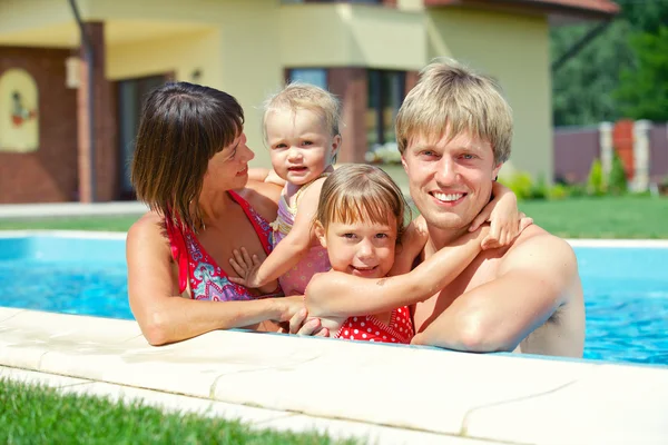 Summer vacation. Happy family of four in swimming pool outdoors — Stock Photo, Image