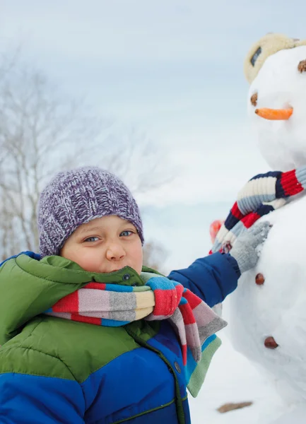 Pojke gör en snögubbe — Stockfoto