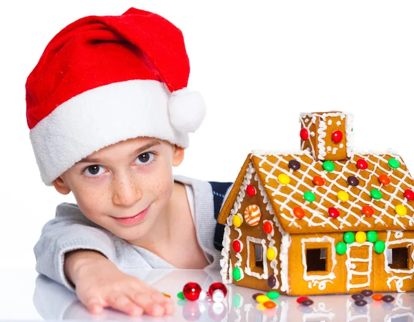 Little boy in Santa's hat with gingerbread house — Stock Photo, Image