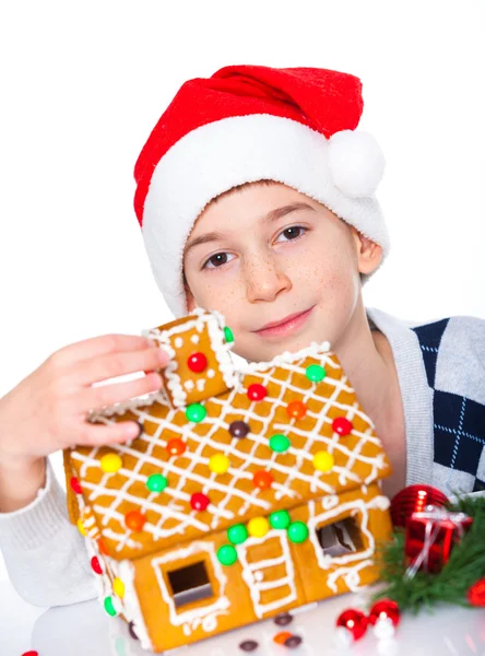 Kleiner Junge mit Weihnachtsmütze und Lebkuchenhaus — Stockfoto