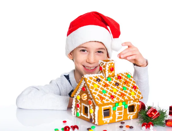 小男孩在圣诞老人的帽子与姜饼屋 — 图库照片