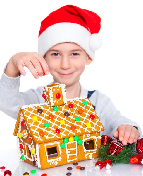 Bambino in cappello di Babbo Natale con casa di pan di zenzero — Foto Stock