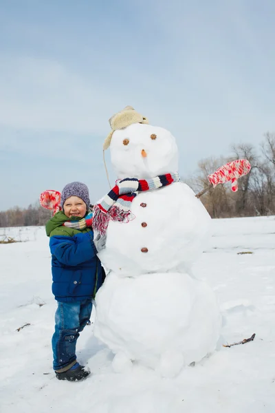 Jongen maakt een sneeuwpop — Stockfoto