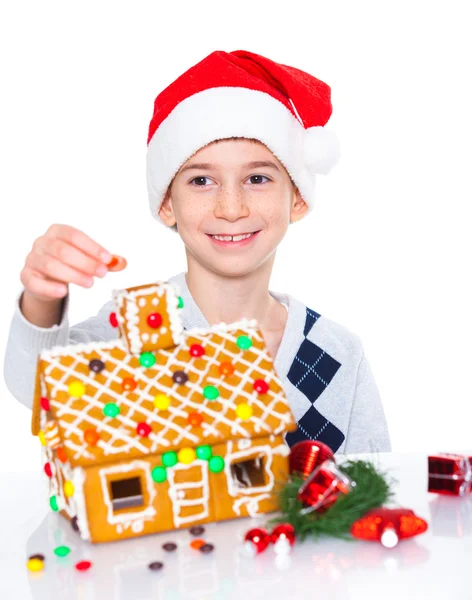 Kleine jongen in kerstmuts met een peperkoek huis — Stockfoto