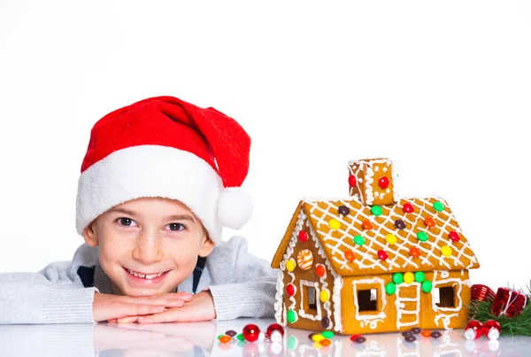 Kleiner Junge mit Weihnachtsmütze und Lebkuchenhaus — Stockfoto