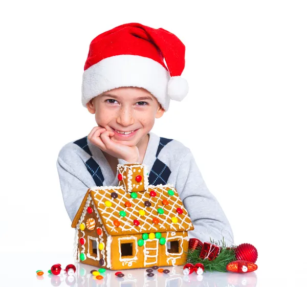 Malý chlapec v Santa klobouk s perníkové chaloupce — Stock fotografie