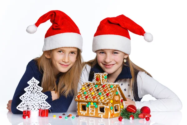 Meninas no chapéu de Papai Noel com casa de gengibre — Fotografia de Stock