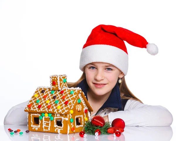 Mädchen mit Weihnachtsmütze und Lebkuchenhaus — Stockfoto