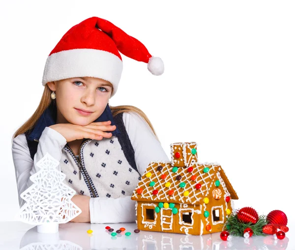 Meisje in kerstmuts met een peperkoek huis — Stockfoto