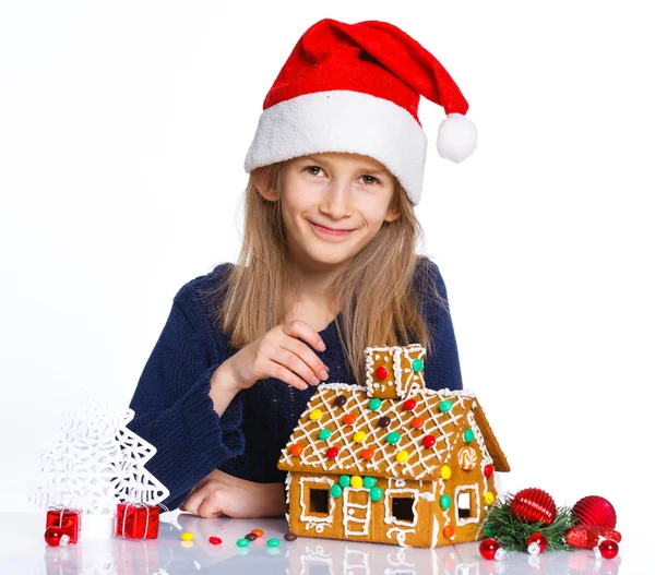 Ragazza in cappello di Babbo Natale con casa di pan di zenzero — Foto Stock