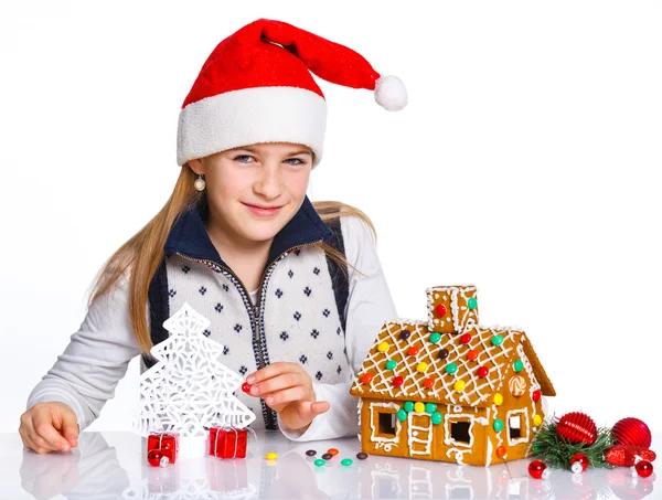 Girl in Santa's hat with gingerbread house — Stock Photo, Image