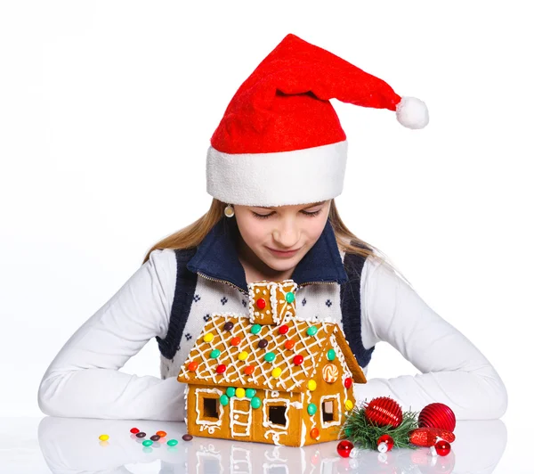 Mädchen mit Weihnachtsmütze und Lebkuchenhaus — Stockfoto