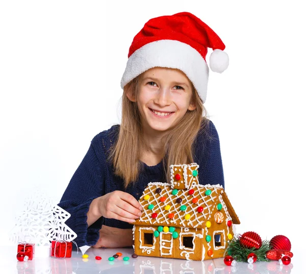 Ragazza in cappello di Babbo Natale con casa di pan di zenzero — Foto Stock