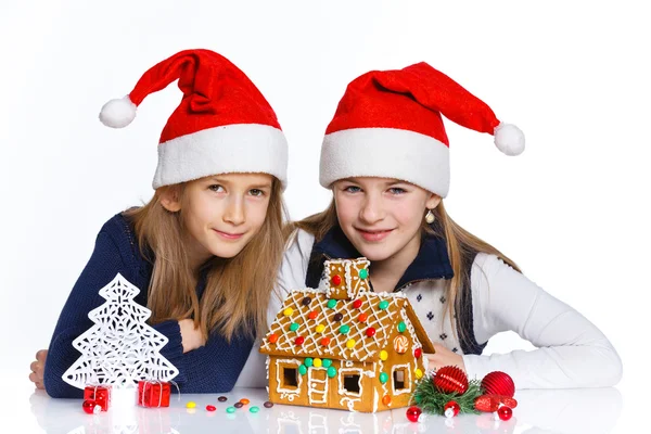 Meninas no chapéu de Papai Noel com casa de gengibre — Fotografia de Stock