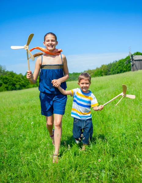 Τα παιδιά στη θερινή ημέρα κατέχει ανεμόμυλος夏の日に子供の風車を保持します。 — ストック写真
