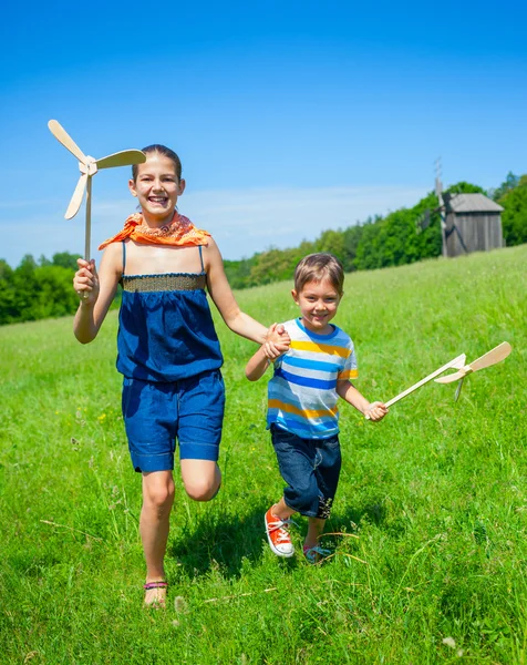 Τα παιδιά στη θερινή ημέρα κατέχει ανεμόμυλος夏の日に子供の風車を保持します。 — Φωτογραφία Αρχείου