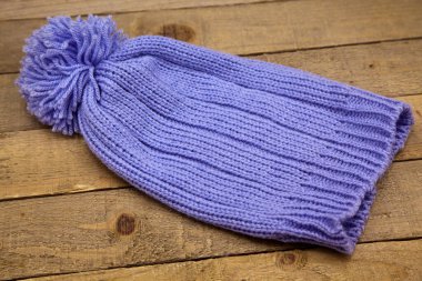 El yapımı yün örgü, ahşap arka planda izole edilmiş mavi şapka.