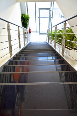 Modern mimari bir evde siyah granit merdiven ve dekoratif krom metal parmaklıklar.