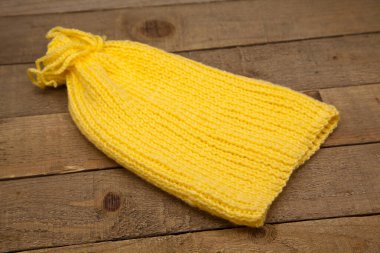 El yapımı yün örgü, ahşap arka planda izole edilmiş kışlık sarı şapka.