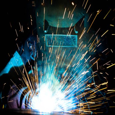 Kaynakçı, metal ekipman üretiminde kıvılcım çıkarmak için meşale kullanır. Profesyonel kaynak ustası.