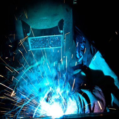 Kaynakçı, metal ekipman üretiminde kıvılcım çıkarmak için meşale kullanır. Profesyonel kaynak ustası.