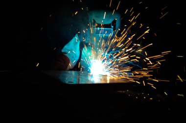 Kaynakçı, metal ekipman üretiminde kıvılcım çıkarmak için meşale kullanır. Profesyonel kaynak ustası.